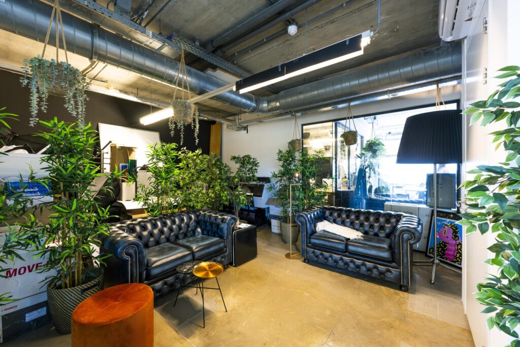 Modern lounge area on Johan van Hasseltweg with black leather sofas, indoor plants, and industrial-style decor.